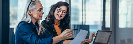 Two women analyzing documents at an office