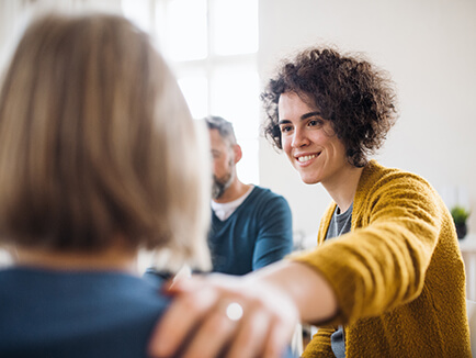 Men and women sitting in a circle during group therapy, supporting each other