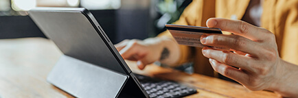 Person at a laptop computer holding a payment card and accessing an online store