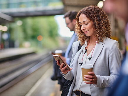 Woman looking at her cell phone while standing on a train station platform