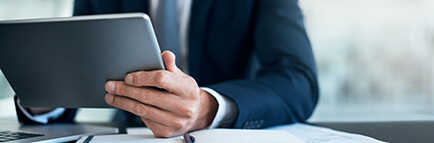 Close up of man at a desk holding a tablet and reading