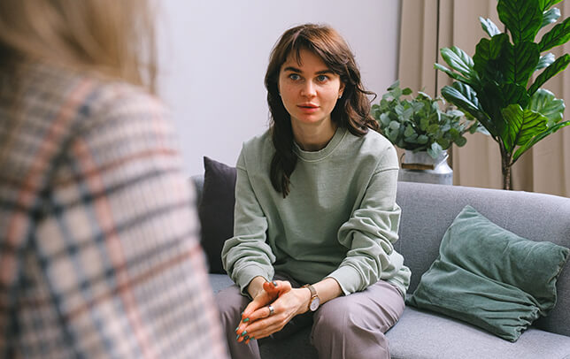 Young woman sitting on a couch speaking with a counselor