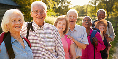 Group of senior friends out for a walk pose in a row along a fence