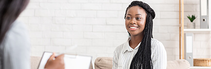 Smiling young woman sitting on a couch while counselor takes notes