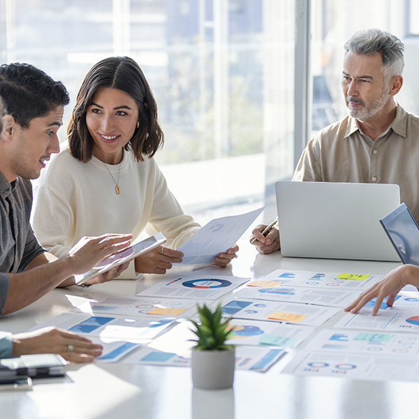 Group of people sitting at table with laptops discussing data